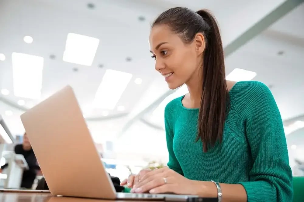 Portrait of a happy female student using laptop computer in university 